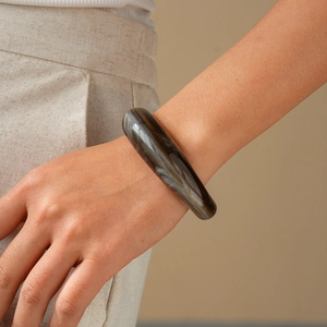 Close-up of a wide brown tortoiseshell acrylic open bangle with amber resin texture