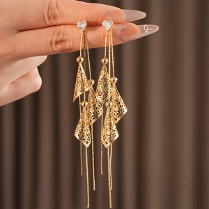 Gros plan sur boucles d'oreilles cœur dorées avec pompons et pendentifs géométriques