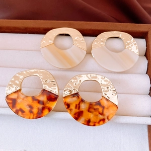 Close-up of retro hammered gold metal and marbled acrylic resin open hoop earrings