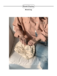 Detail of a creamy beige pleated shoulder bag with chic bow accents and a gold chain strap