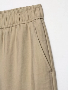 Detail of khaki wide-leg pants with elastic waist and side pockets in cotton-linen fabric