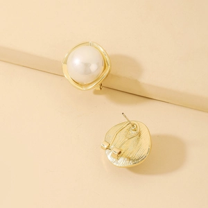Detailed view of gold geometric pearl earrings with a white pearl and irregular metal frame