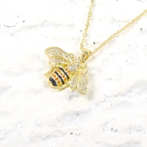 Luxurious bee pendant necklace with zircon pavé and gold plating on white background