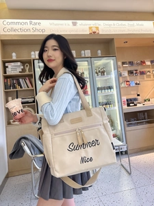 Detail of beige canvas tote bag with Summer Nice embroidery in a cafe setting