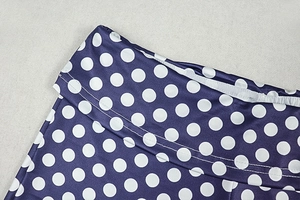 Detail of elastic waistband and white polka dot print on purple high-stretch fabric