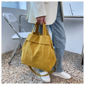 Lifestyle shot of large yellow nylon tote bag worn over the shoulder with casual outfit