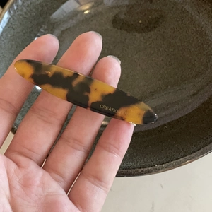 Macro detail of amber acetate hair clip with leopard pattern and golden brand lettering