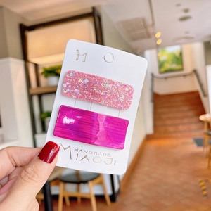 Detail of pink glitter and purple rectangle hair clips on a white display card