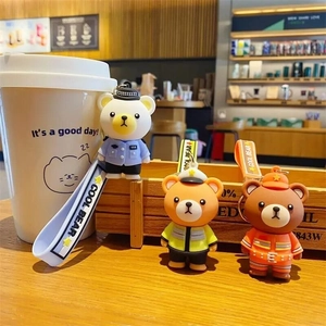 Cute cartoon police and firefighter bear keychains on a wooden surface in a cafe setting