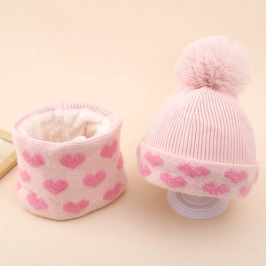 Close-up of pink knit hat and scarf set with heart patterns and warm fleece lining