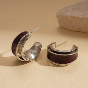 Detail of silver C-shaped double-layer hoop earrings with deep burgundy enamel inlay