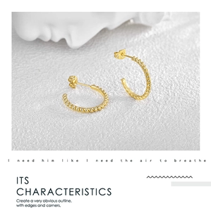 Close-up of gold-plated spiral hoop earrings with elegant twisted texture on white background