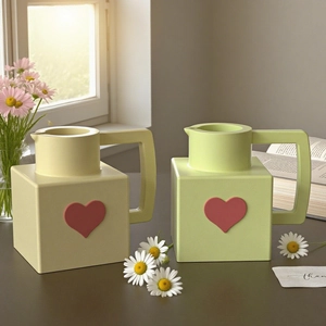 Modern square ceramic vase set with heart decor and handle in a sunny home setting