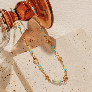 Detail of beaded necklace with sky blue beads and golden flowers on stone
