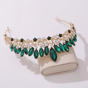 Macro shot of bridal crown with green crystals and rhinestones on gold alloy band