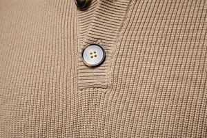 Detail of high-quality camel knit sweater with ribbed texture and premium buttons