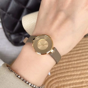Close-up of minimalist gold women's watch with brown leather strap on wrist