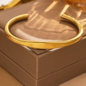 Detail of 18k gold plated stainless steel cuff bangle with smooth polished tubular structure