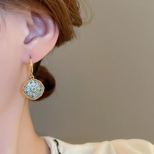 Close-up of vintage floral earrings with blue enamel and zircon on gold plating