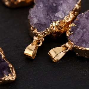 Natural amethyst crystal geode pendant with gold-plated edges on dark background