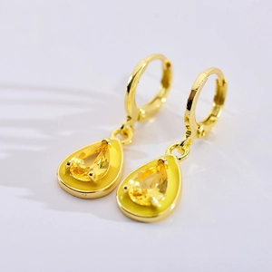 Detail view of yellow teardrop gem earrings with golden enamel and polished hoop finish