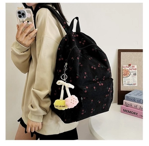 Detail of black corduroy cherry print backpack with fuzzy cherry keychain charm