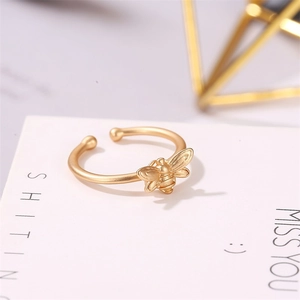 Close-up of matte gold bee open ring featuring intricate wings on a white card