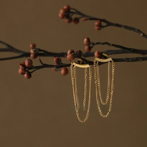 Detail of 18K gold-plated tassel chain earrings hanging on an elegant branch display
