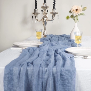 Detail of blue wrinkled cheesecloth table runner draped over a white tablecloth