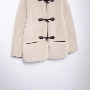 Manteau tendance en fausse fourrure beige avec boutons brandebourg et lanières en cuir