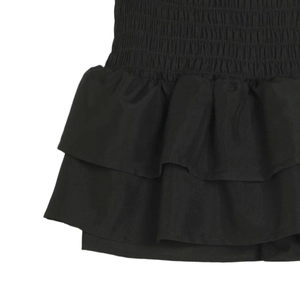 Détail d'une jupe noire à volants avec taille haute élastique smockée et ourlet multicouche