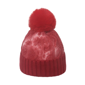 Detail of red and white tie-dye knit beanie with fluffy pom-pom and thick cable texture