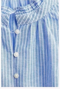 Macro shot of vertical blue striped linen top with ruffle collar and white buttons