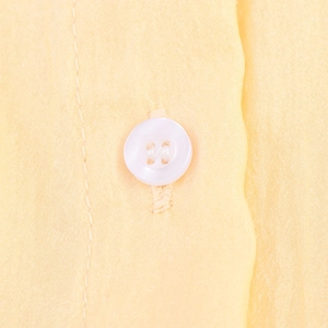Robe jaune pâle avec bouton blanc à quatre trous et détails de texture délicats