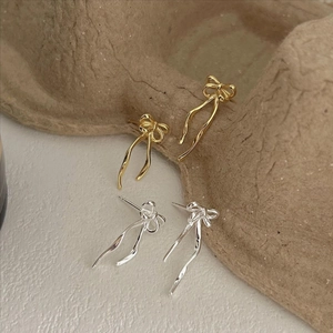 Elegant 925 silver bow tassel earrings in gold and silver finish on textured background