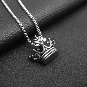 Macro shot of silver stainless steel crown pendant on box chain over black leather