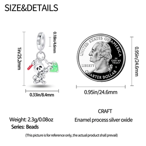 Silver skull charm with green enamel detail and dimensions shown next to a coin
