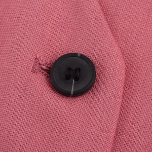 Gros plan détaillé d'un bouton noir sur le tissu en tweed rose d'un ensemble d'été