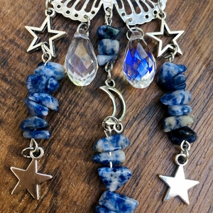 Macro detail of silver butterfly and moon charms with blue natural stones and crystals
