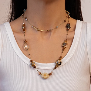Detail of bohemian double-layer necklace with amber beads and ceramic floral charms
