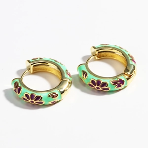 Detail of gold huggie earrings with mint green enamel and purple floral patterns