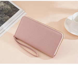 Pink lychee texture long wallet with wrist strap on an elegant lifestyle background