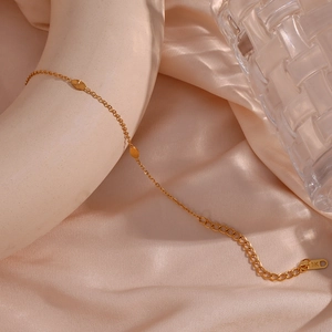Detail of 18K gold-plated stainless steel bracelet with oval charms on champagne silk