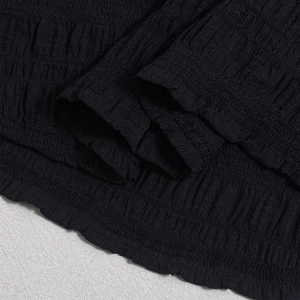 Close-up of black ruched fabric texture and stitching detail on backless camisole dress