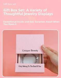 Pink textured drawer jewelry box featuring a grey beaded bracelet inside the packaging