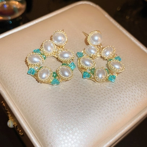Macro view of vintage floral earrings with faux pearls and green crystal accents