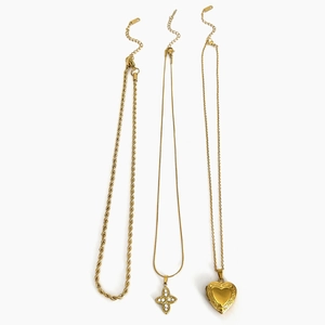 Ensemble de trois colliers superposables en acier titane doré 18K avec pendentifs cœur et croix