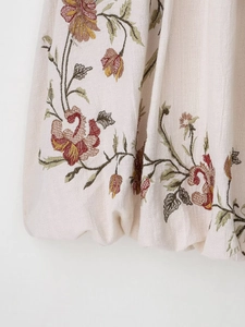 Detail view of retro floral embroidery on beige cotton-linen dress with vivid stitching