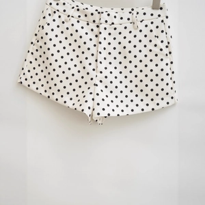Stylish white high-waisted shorts with black polka dots featuring side pockets