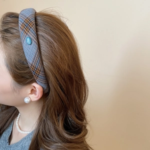 Detail of grey plaid headband with orange stripes and oval Korea metal tag on model
